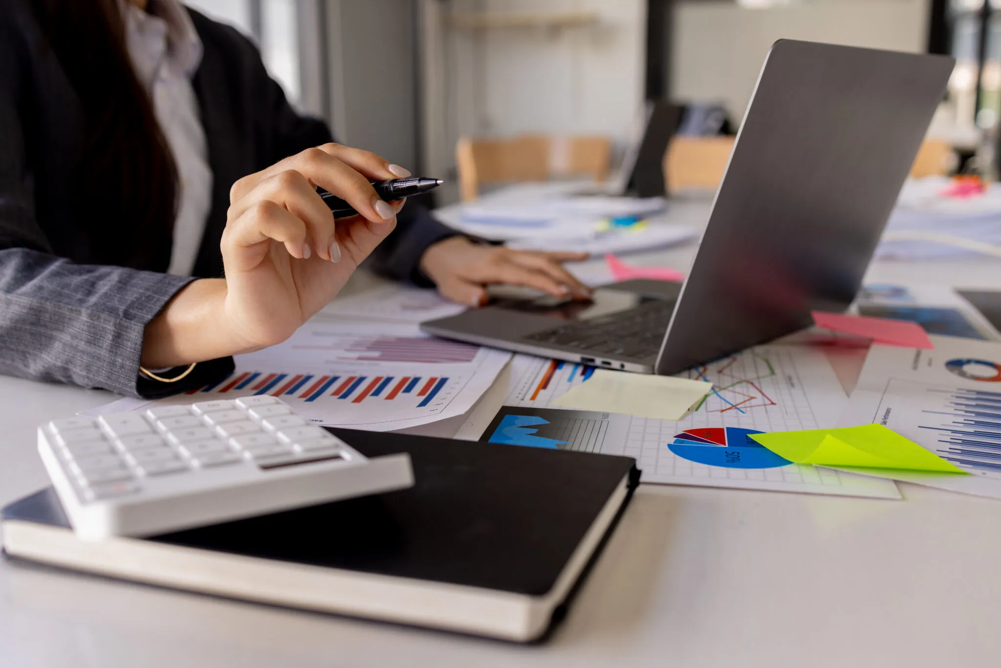 Business analyst reviewing financial charts and data on a laptop at a desk